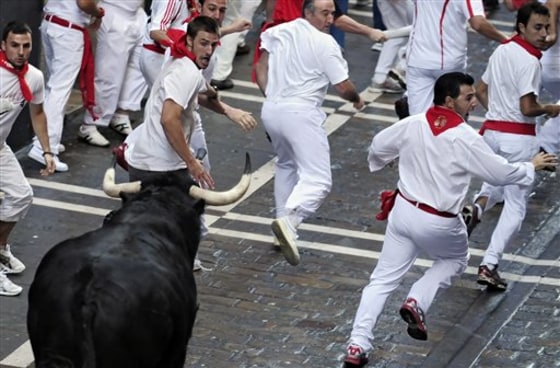 Revelers run away from a fighting bull during the fourth run of the San Fermin festival in Pamplona, northern Spain, on Saturday.